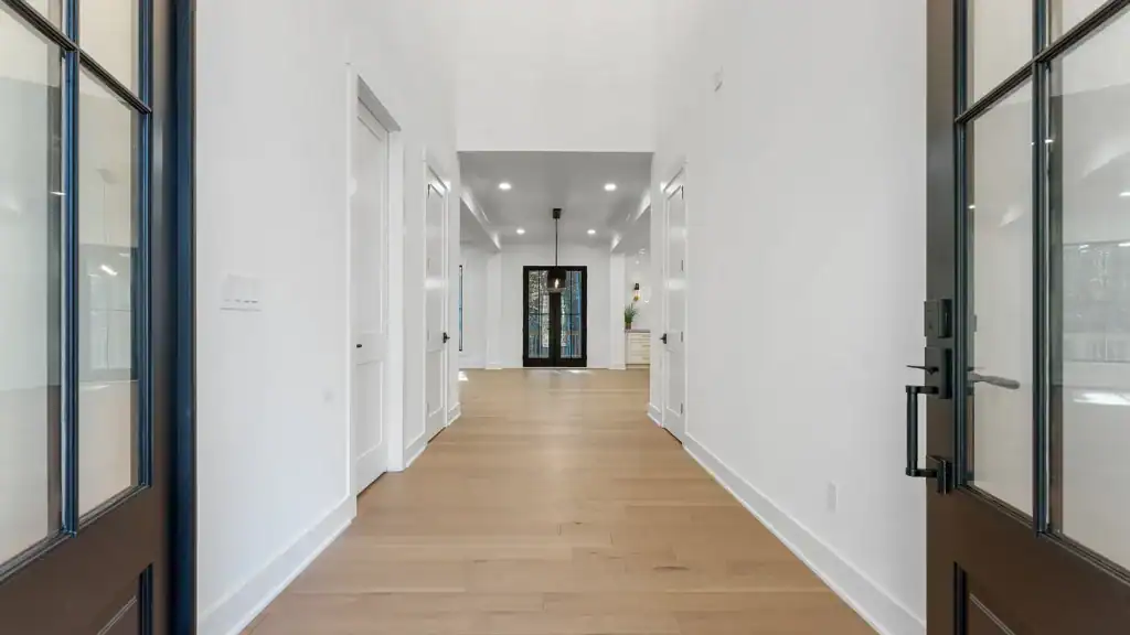 450c7fafa915356d91dd810365875e30-uncropped_scaled_within_1536_1152 Bright modern home interior with sleek black entry doors, white walls, and hardwood flooring, showcasing Bertamini Development's craftsmanship.