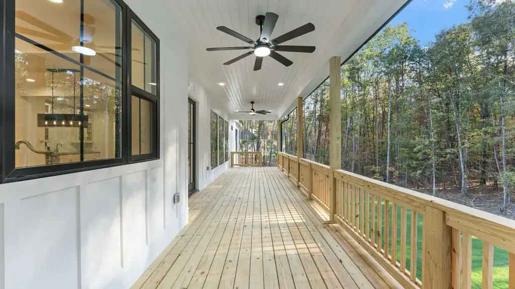 845c9aee4a553a1c7246d1d0b4e6f510-uncropped_scaled_within_1536_1152 Elegant outdoor porch with ceiling fans and wooden railings, surrounded by lush trees for natural serenity.