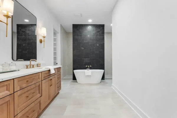 Luxurious modern bathroom with freestanding bathtub, black accent wall, and elegant wooden vanity.