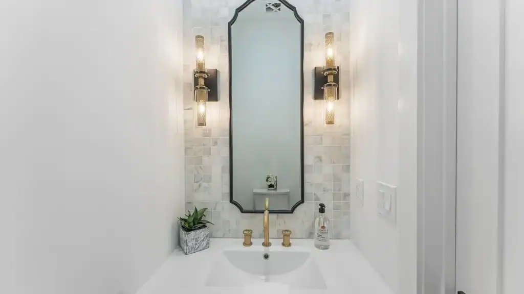 ea42257a92e4488598c463a47f4ac3c3-uncropped_scaled_within_1536_1152 Elegant bathroom vanity with gold fixtures and mosaic tile backsplash, showcasing modern design and lighting.