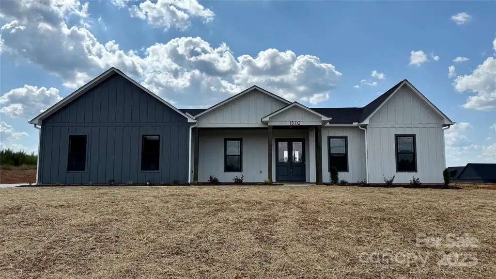 3ef973642bc54b1bf555bba0629f8d6a-uncropped_scaled_within_1536_1152 Modern custom home with contrasting blue and white exterior siding, stylish design, and spacious front yard.