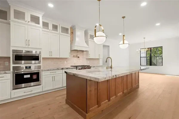 Contemporary white and wood kitchen with island, pendant lighting, and large window for natural light.