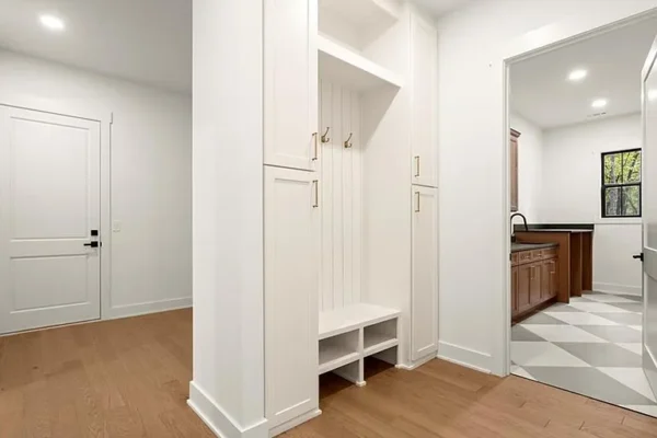 Modern white built-in storage bench and coat hooks in a bright, newly renovated home.