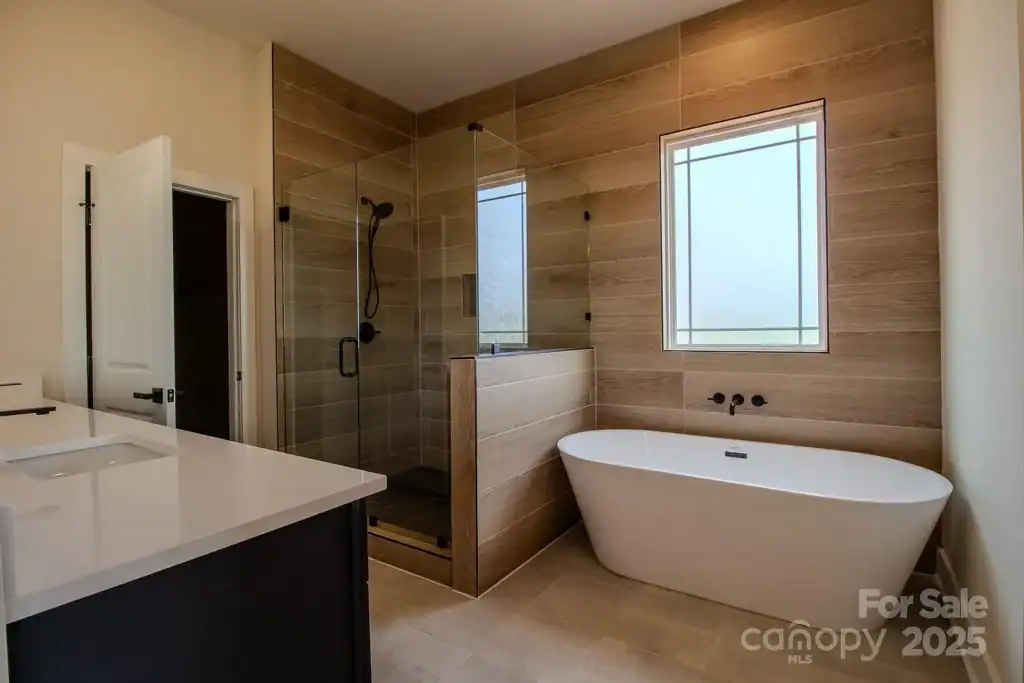 963a3426079a08b56bdb7b980095e3b9-uncropped_scaled_within_1536_1152 Modern bathroom with walk-in shower, freestanding tub, and neutral wood tile accents.
