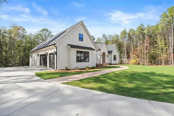 Modern white farm-style home with black accents by Bertamini Development, set on a spacious landscaped property.