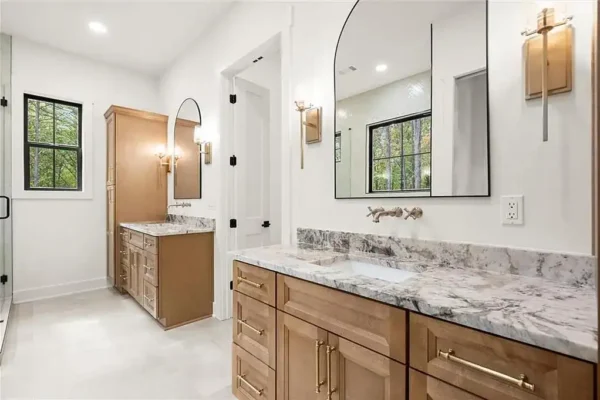 Elegant modern bathroom with double vanities, marble countertops, and stylish lighting fixtures.